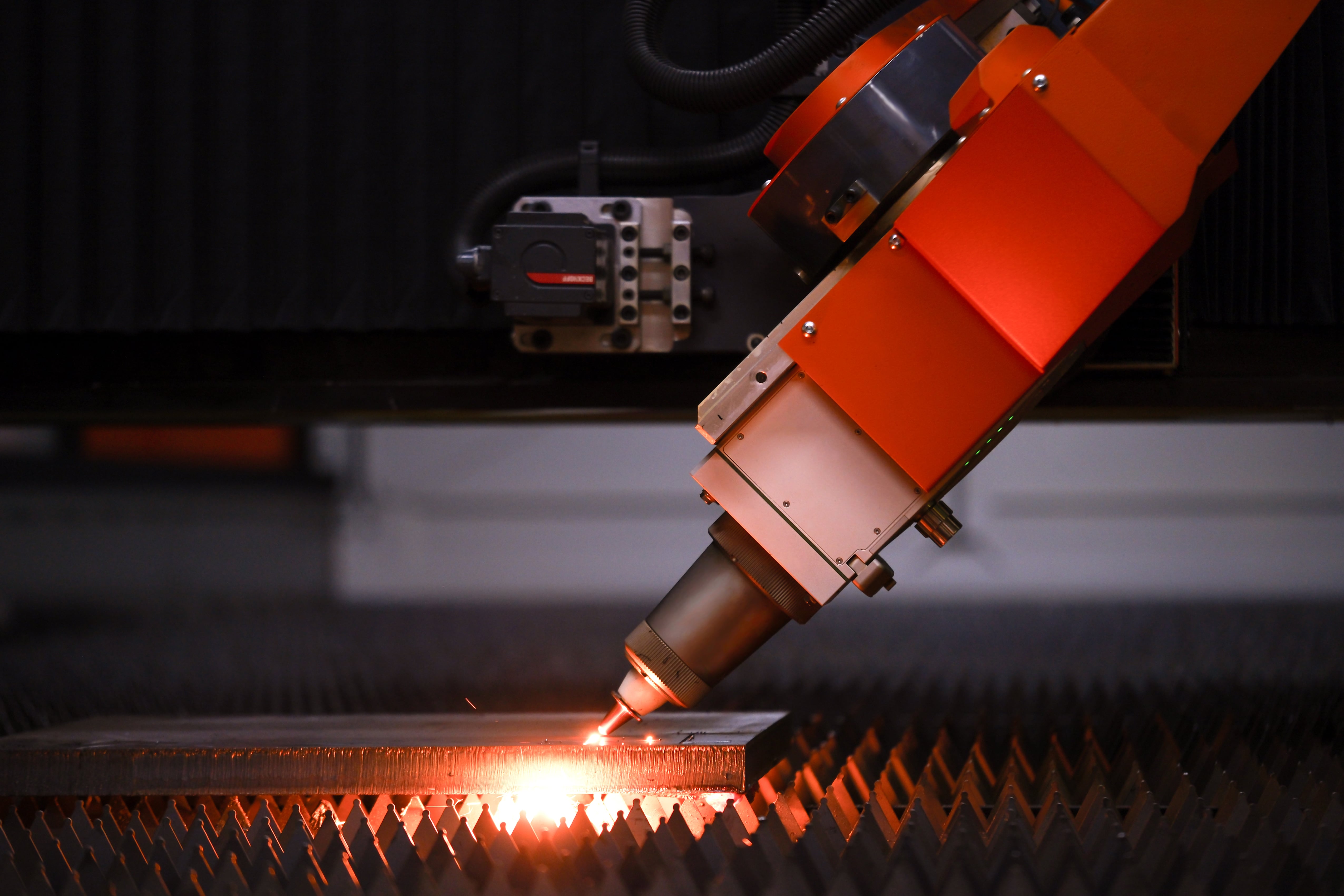 Bevel cutting on the shop floor: the orange NLCH head at the cut point with sparks at the kerf